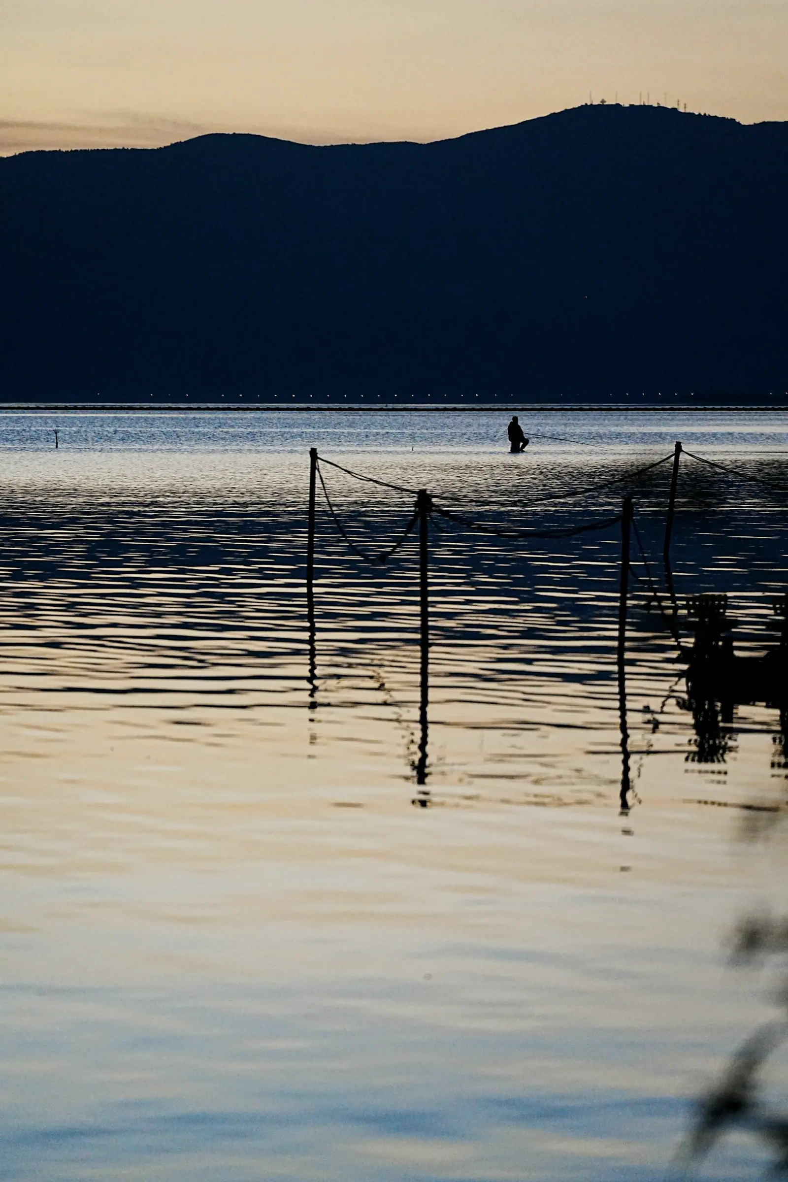 The lake going dark, the silhouette of one person on a boat