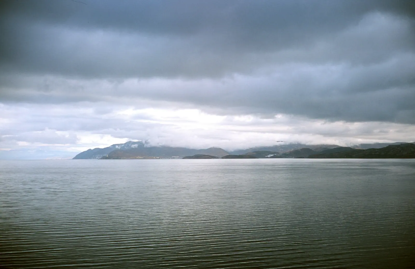Erhai under an overcast sky, cloud hanging low, a line of mountains in the distance