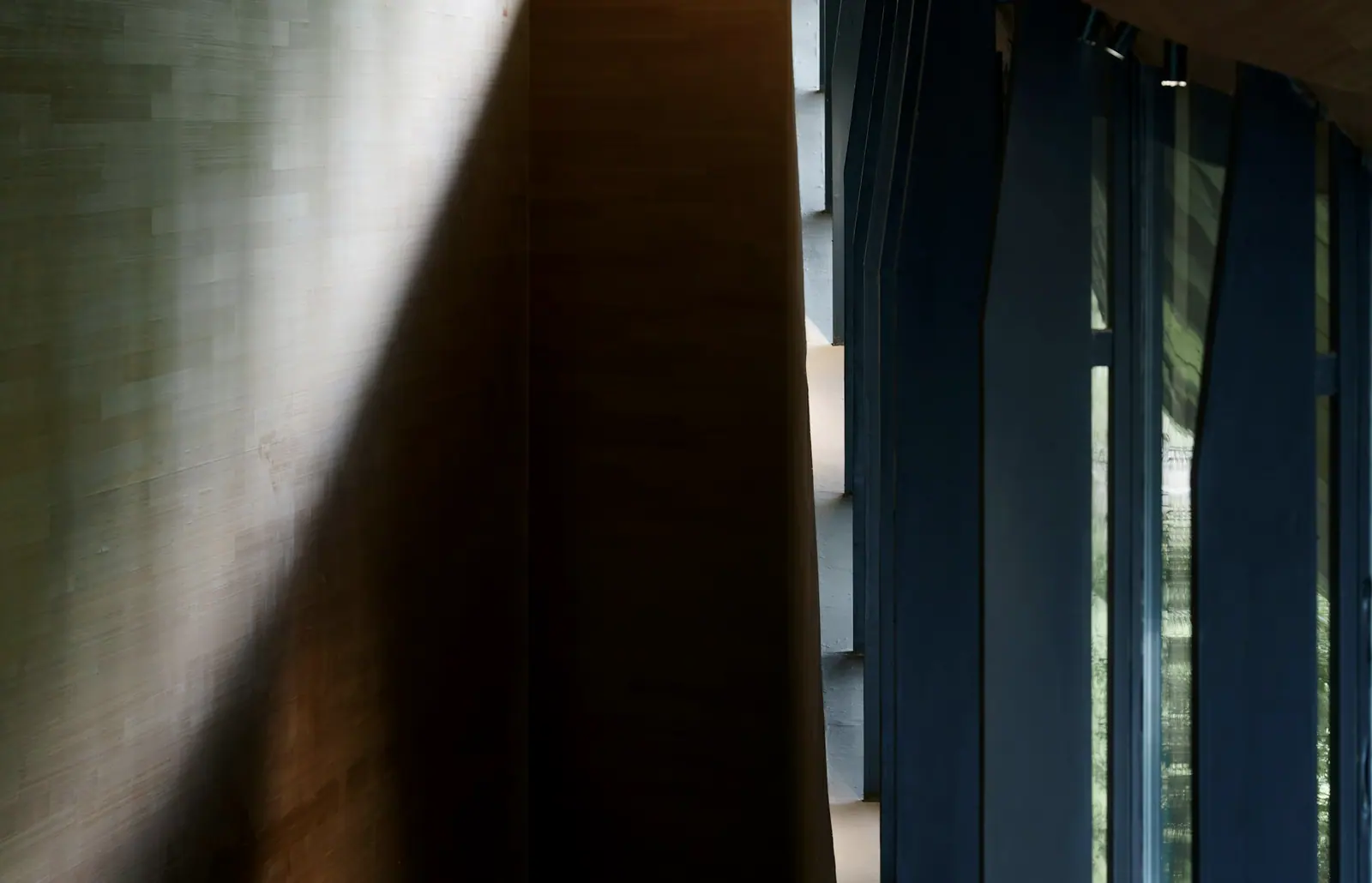 Sunlight through a blue curtain, laying one stripe of light across a rough wall