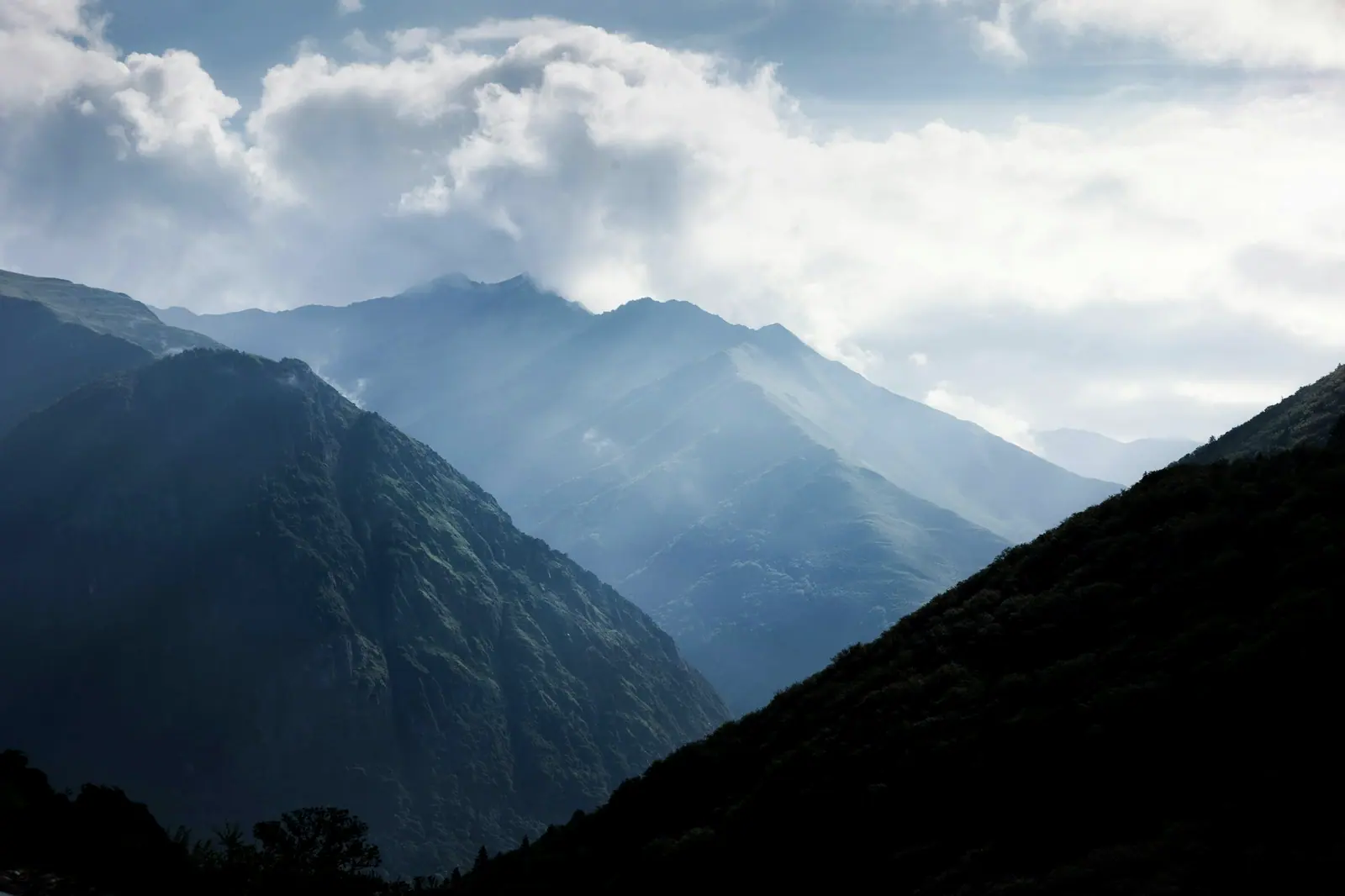 A blue-grey valley half covered by cloud, light leaking through the gaps