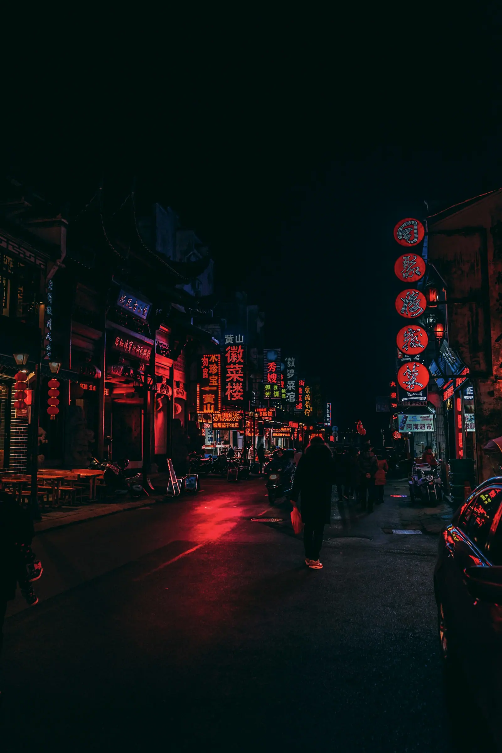 Someone standing at the roadside with a few red lanterns glowing behind