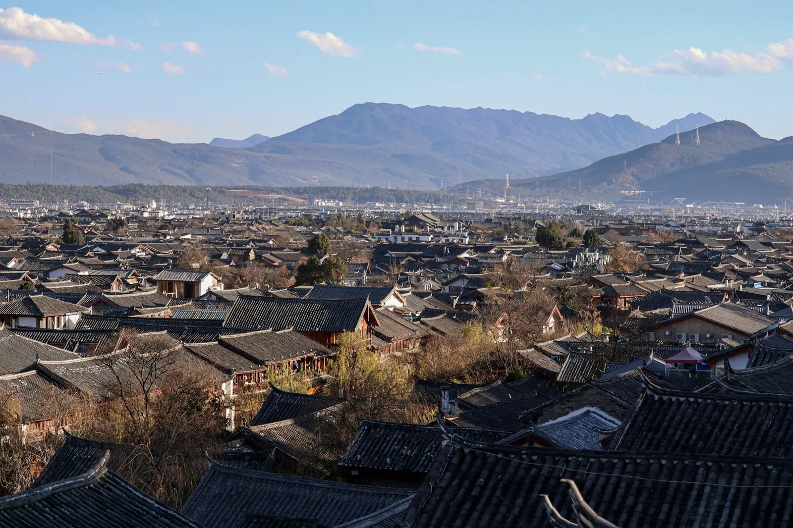 A whole old town of grey tiled roofs beneath distant mountains