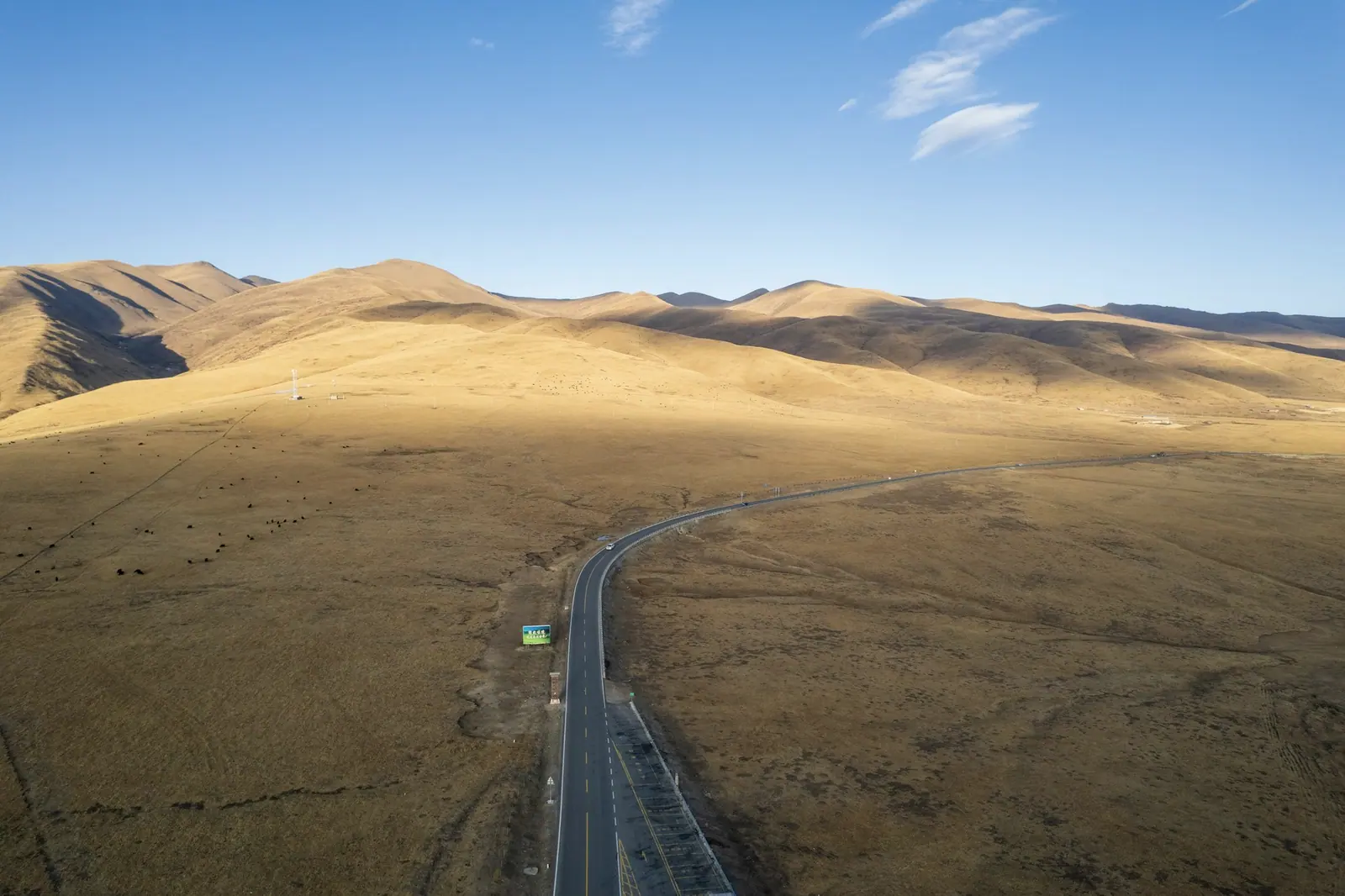 A straight road running out toward golden grass hills