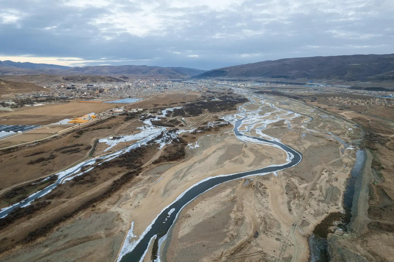 From above, a river splitting into thin threads across a dry gravel bed