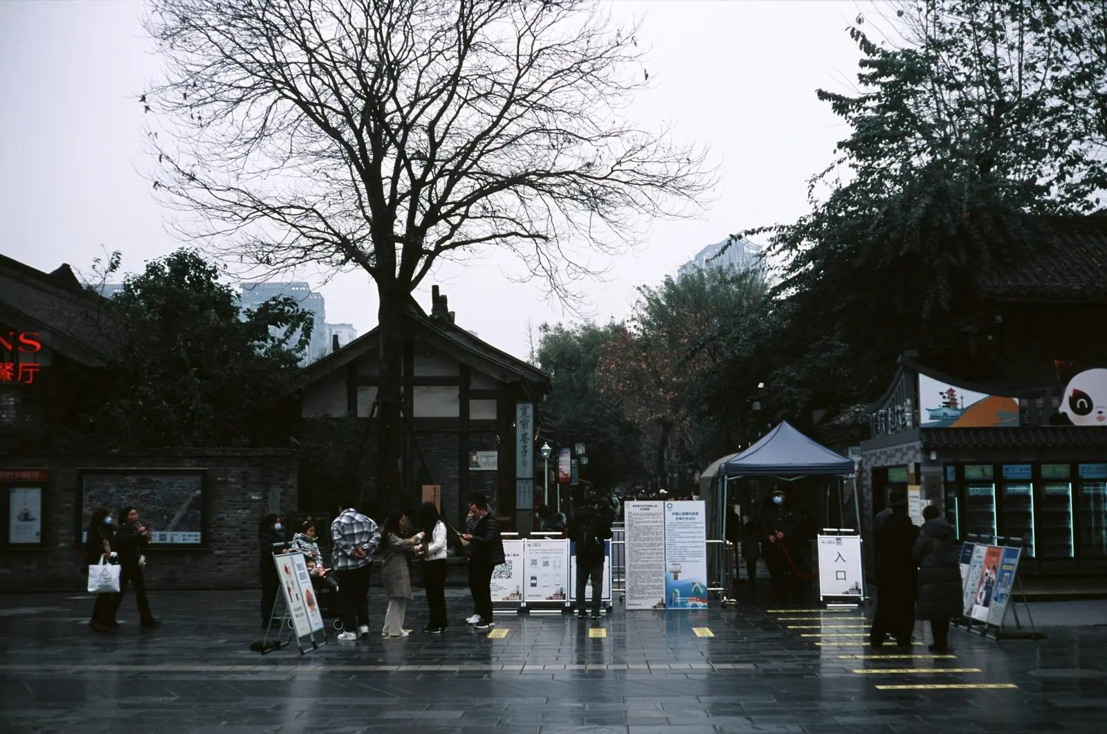 Rain at an old street corner, a few people with umbrellas standing on the wet ground